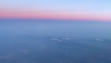 View out of the window of a plane of a beautiful pink horizon.