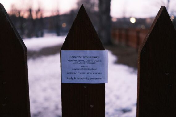 A photo of a fence post with a white sticker on it asking "what would you most likke to change about yourself?"